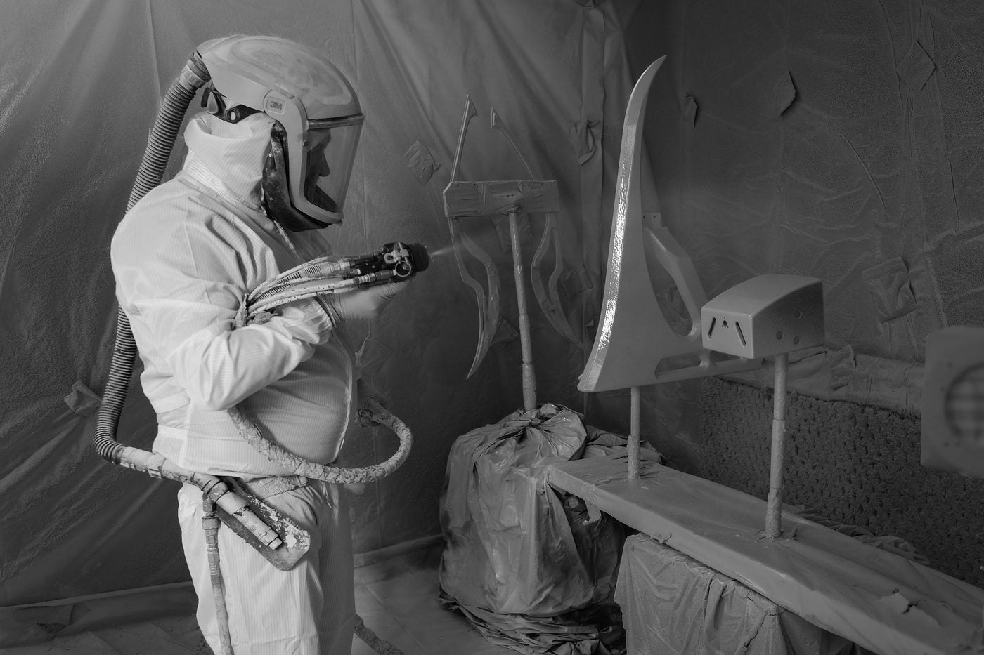 A craftsperson in protective gear applying gel coat to a gantry element