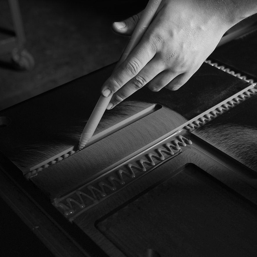 A hand applying adhesive along a toothed composite joint