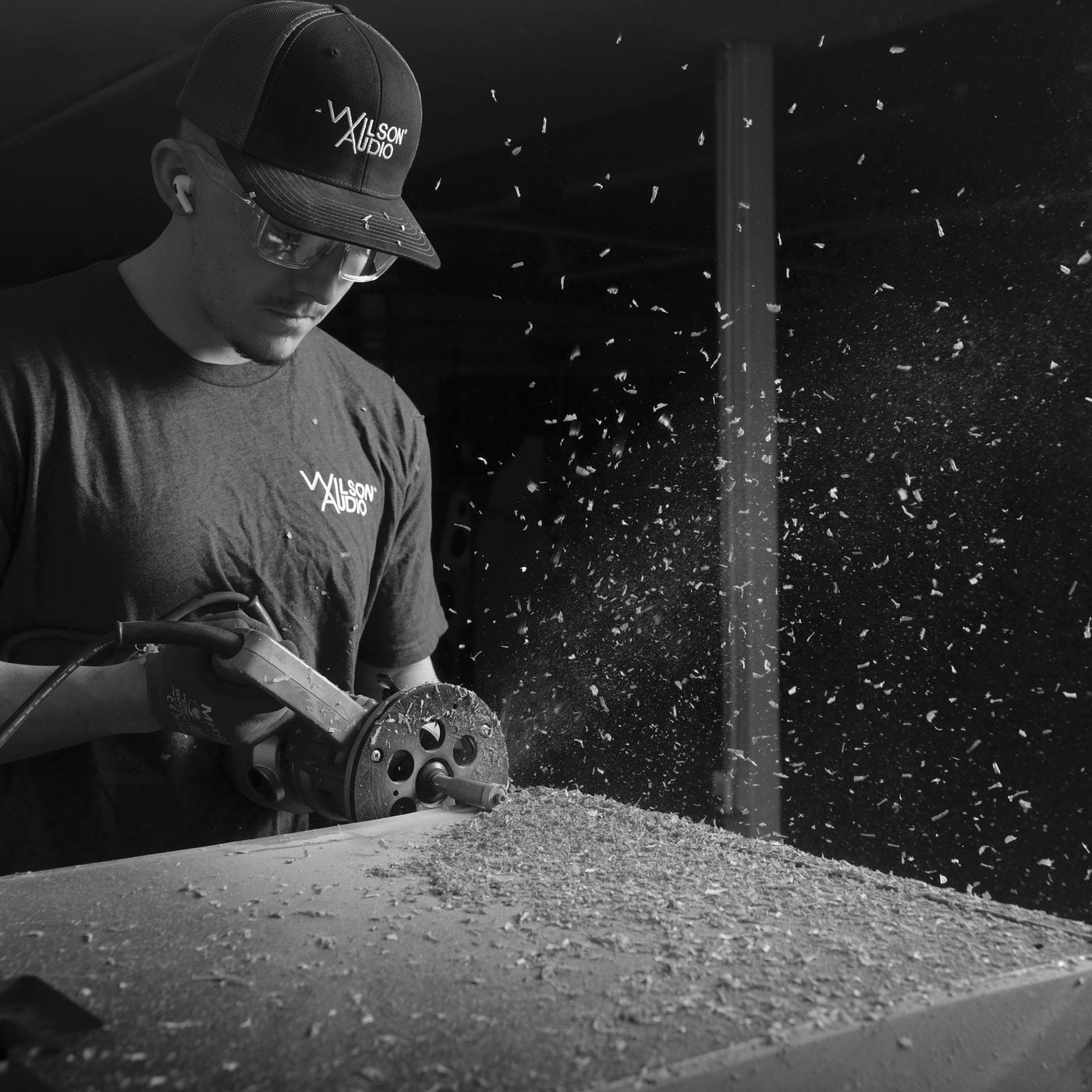 A craftsperson routing a composite panel, chips flying